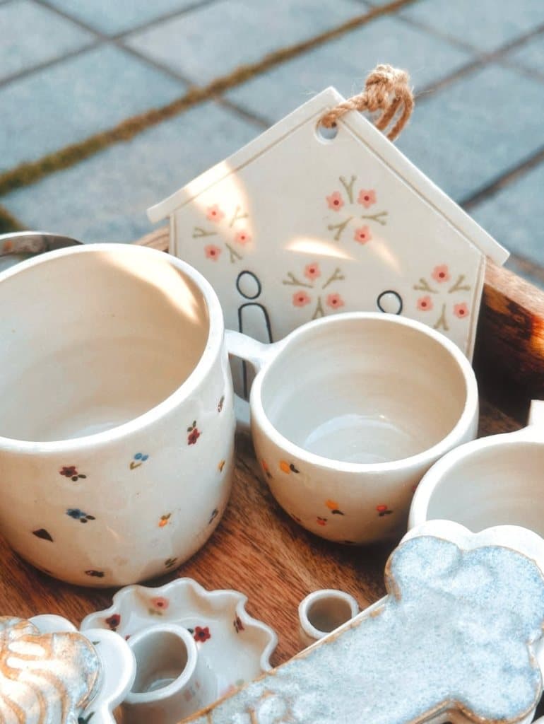 Handcrafted ceramic mugs and keepsake plaque on wooden tray in morning sun