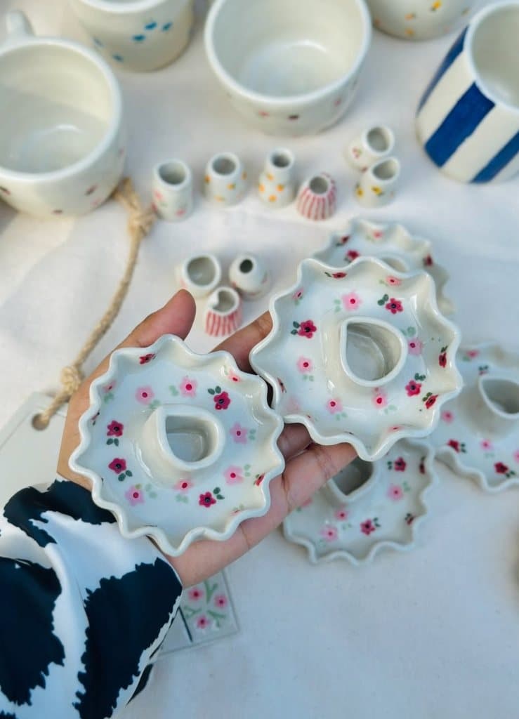 Hand holding two ruffled floral ceramic candle stands